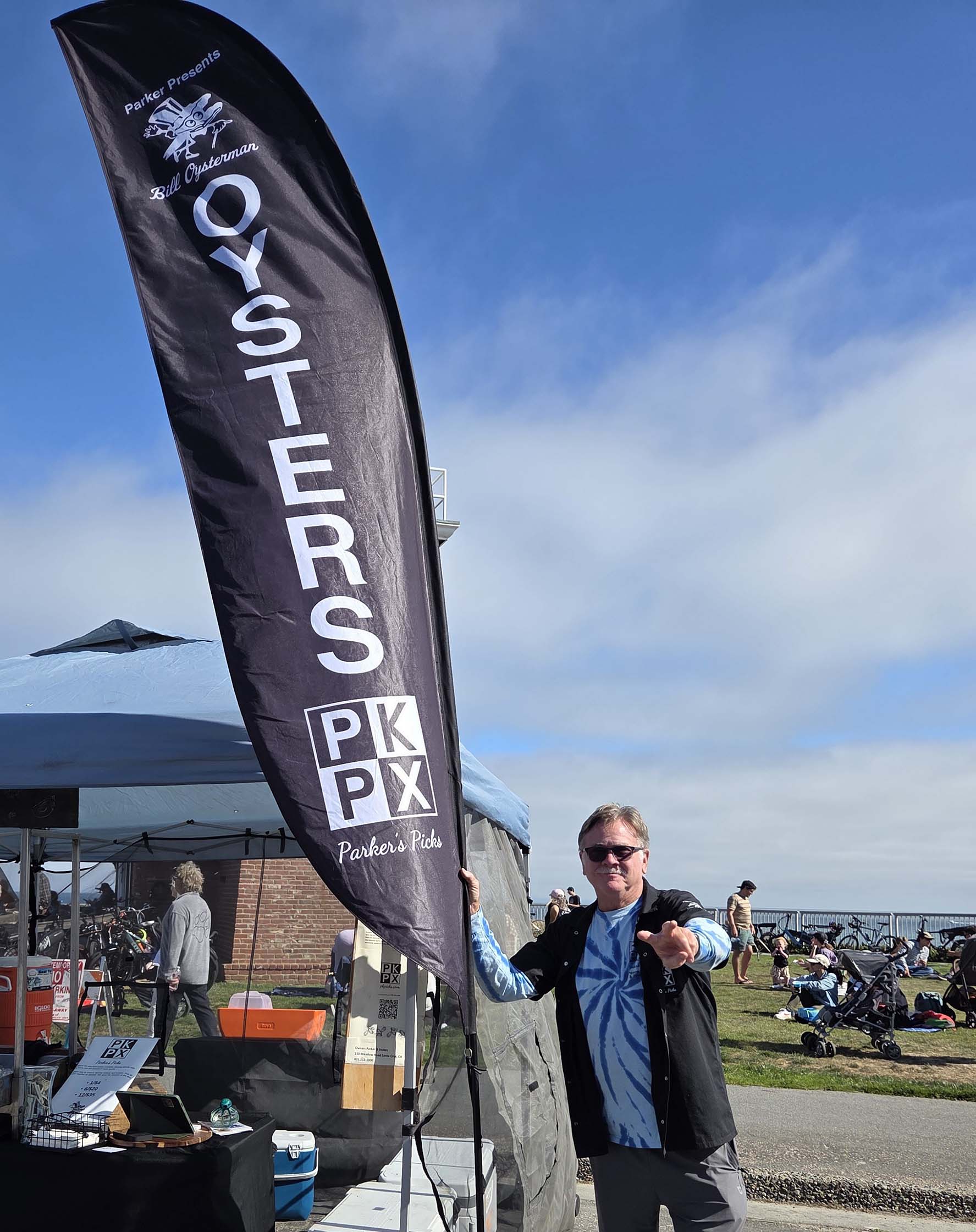 Parker holding a Parker's Picks oysters feather flag at an outdoor event
